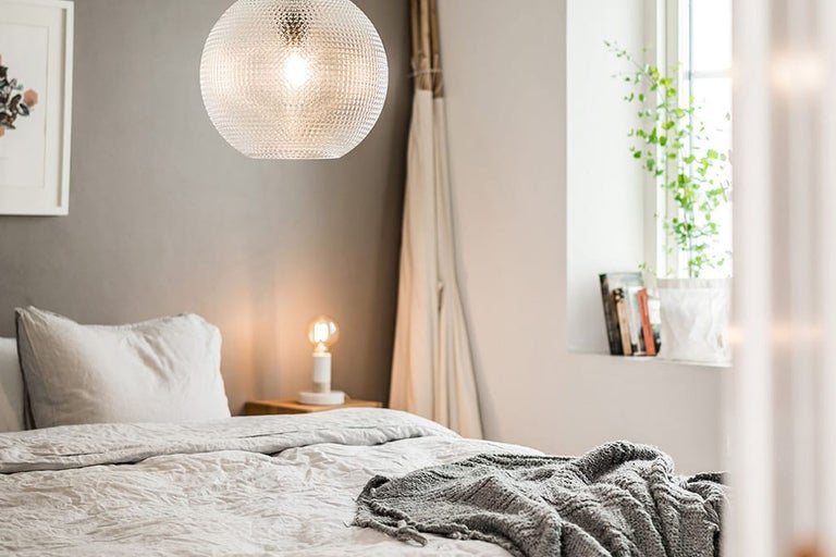 Sovrum med säng, sängbord och rund hänglampa