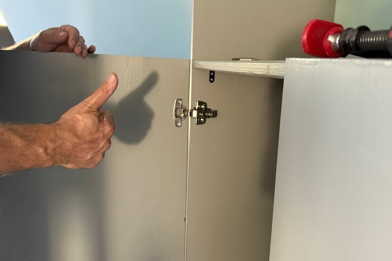 Närbild av ett monterat skåp med en hand som visar en tumme upp