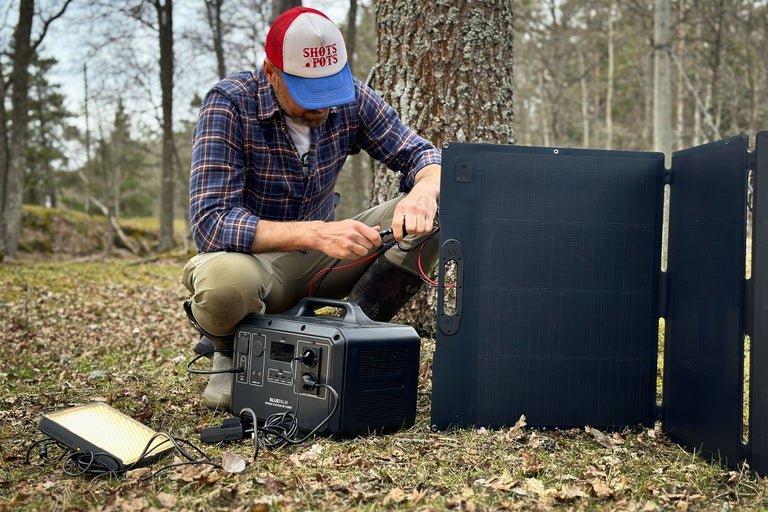 Man ansluter solpanel till bärbar kraftstation utomhus