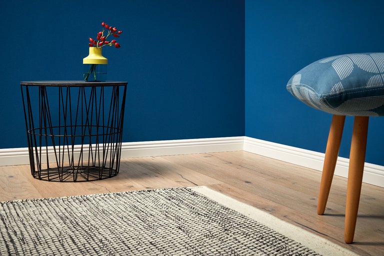 Vardagsrum med en matta, ett sidobord, en vas och en pall.