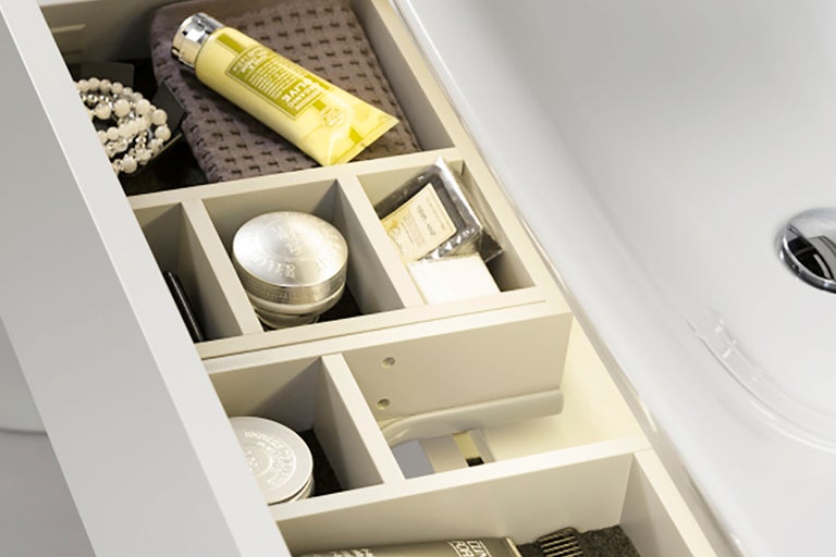Öppen låda i ett tvättställsskåp med diverse badrumsartiklar