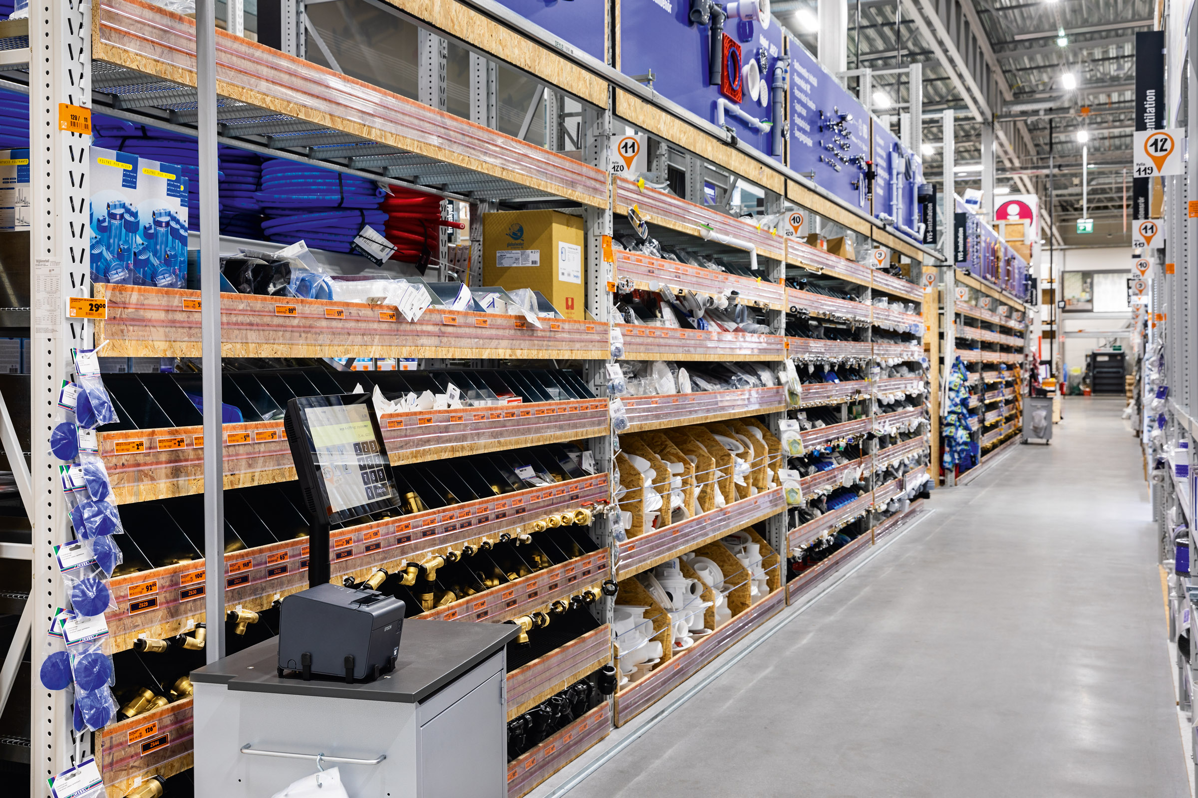Gångvy i en Hornbach-butik med hyllor fulla av sanitetsartiklar och installationsteknik.