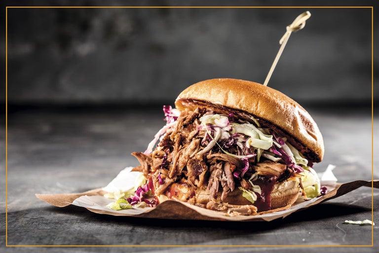 En pulled pork hamburgare med coleslaw på en bit papper.