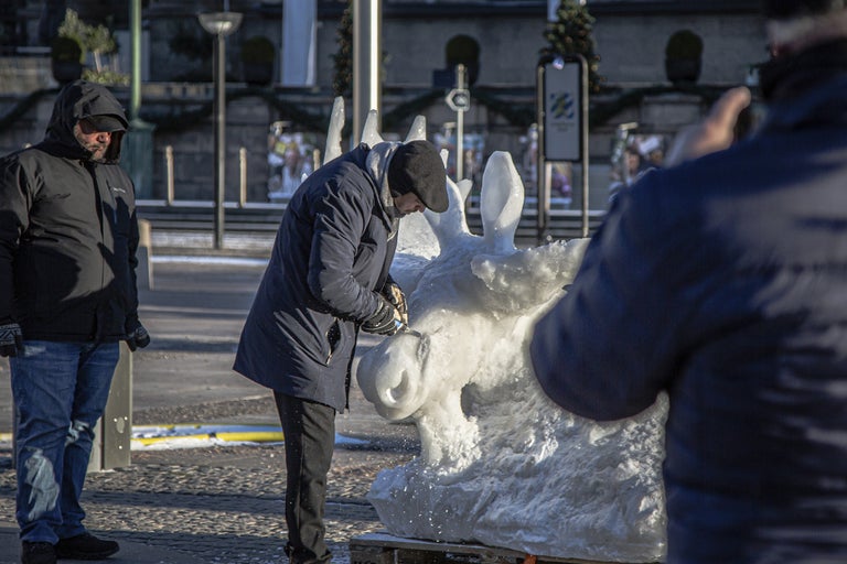 Man bearbetar en skulptur av is med ett verktyg.