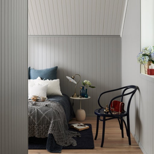 Sovrum med säng, stol och sängbord i en mysig stil.