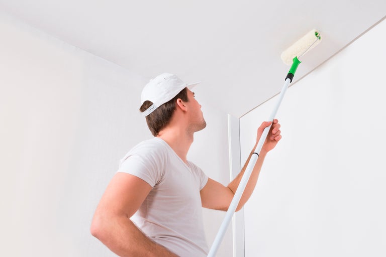Man målar tak med färgroller och teleskopstång