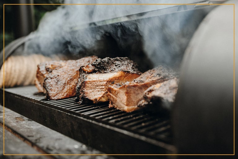 Rökt kött på en grill med rökutveckling