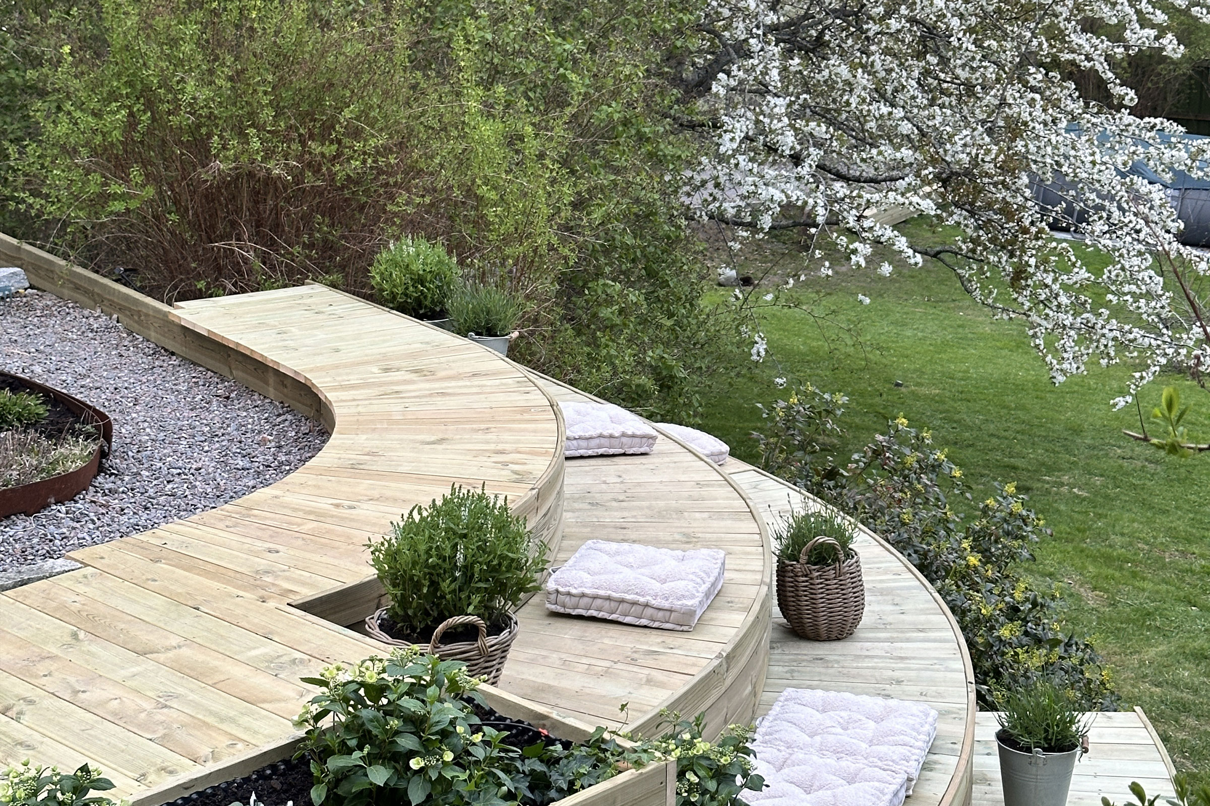 Anlagd trädgård med träterrass, dekoration och plantering.