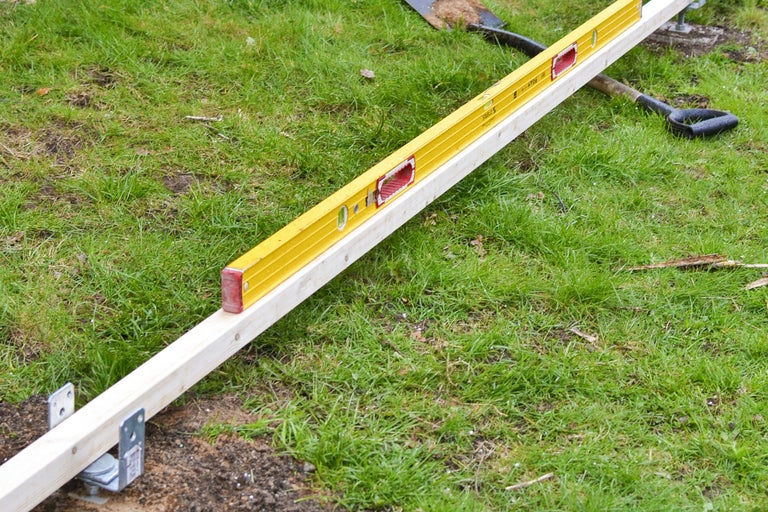 Gul vattenpass på en träplanka i trädgården.