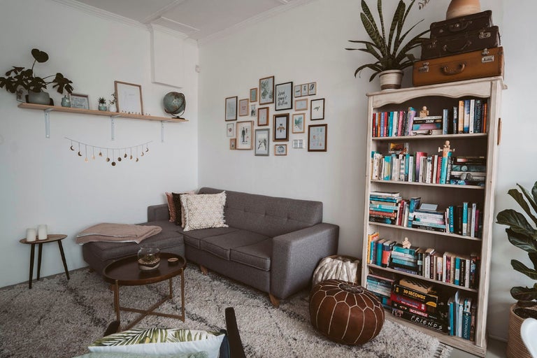 Vardagsrum med grå soffa, bokhylla och dekorativ väggmonterad galleri