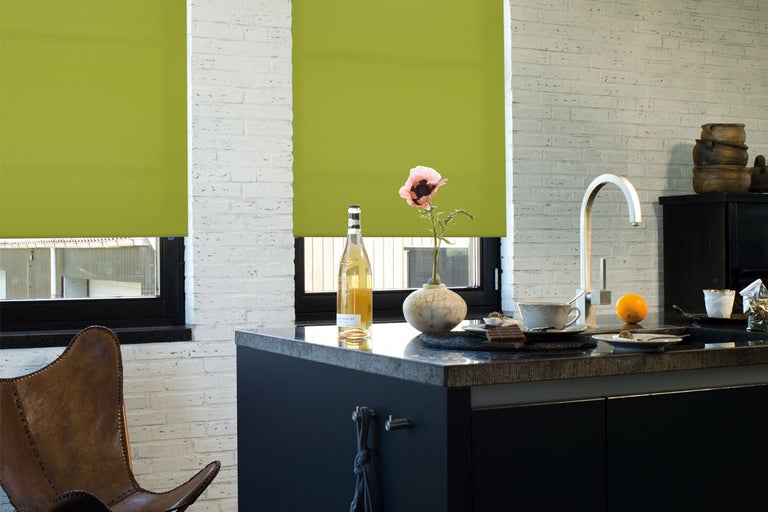 Ljust kök med gröna rullgardiner för fönstren och dekoration på arbetsytan