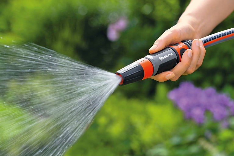 Trädgårdsdusch i handen medan du vattnar växter
