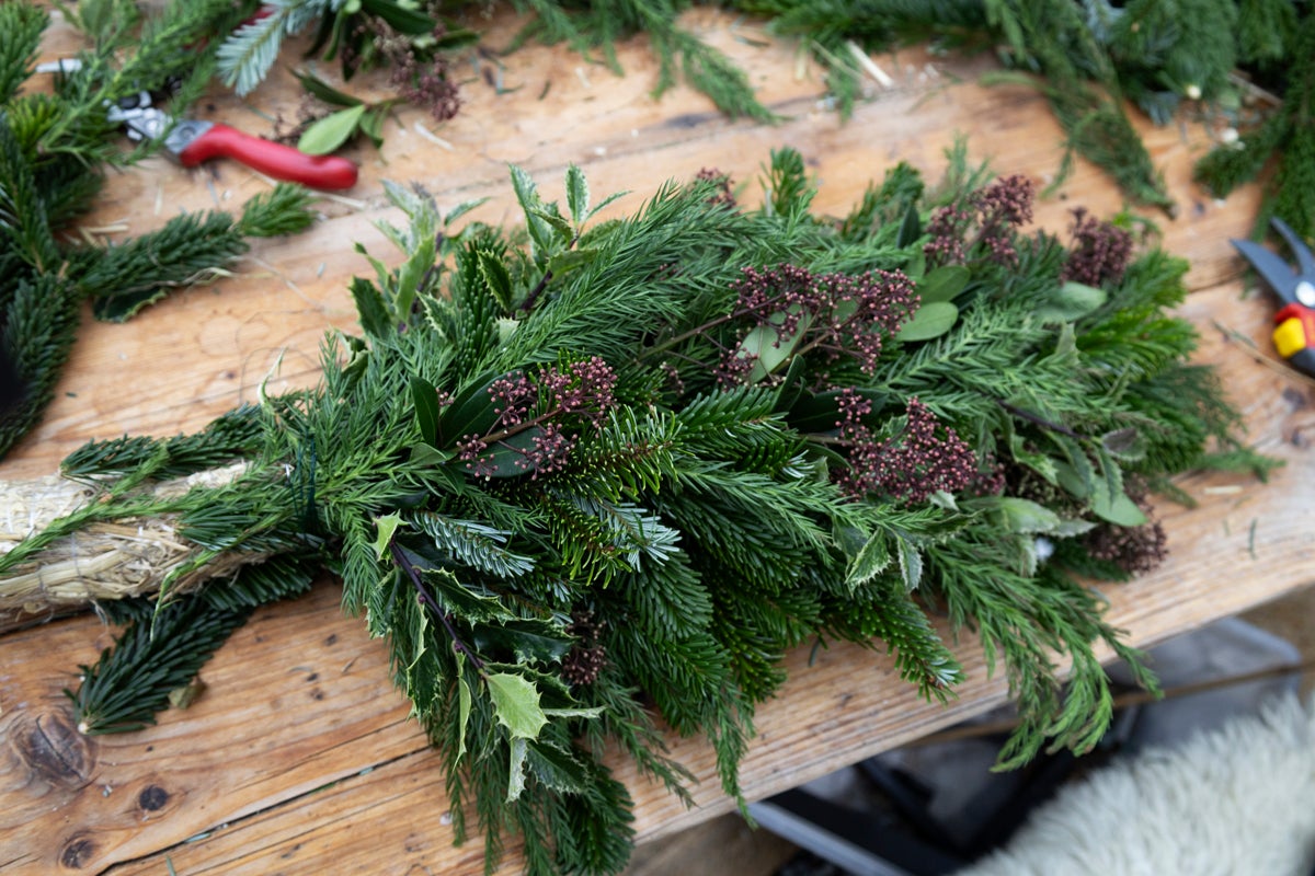 Dekoration med grangrenar, järnek och bär på ett träbord