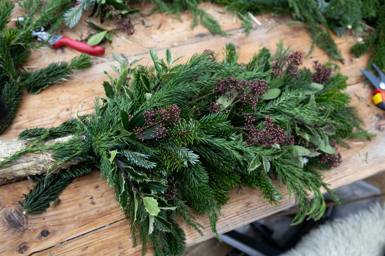 Dekoration med grangrenar, järnek och bär på ett träbord