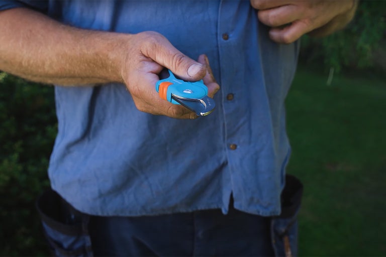En person håller en trädgårdssax i handen.