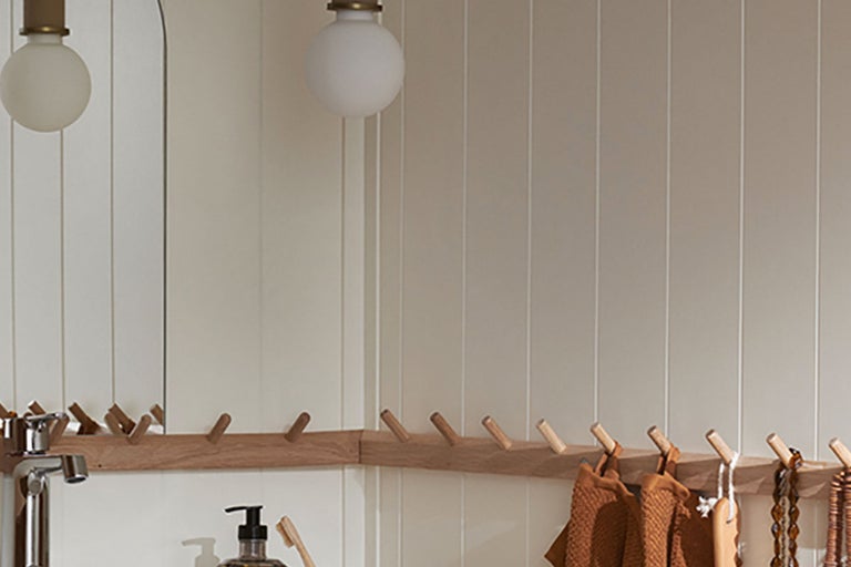 Ljust badrum med träkrokar, handdukar och belysning