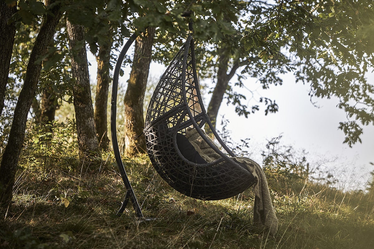 Hängfåtölj i rotting med metallram i trädgården