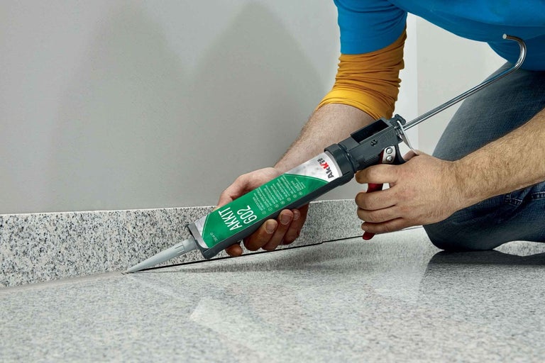 Användare applicerar tätningsmedel på en kakelsockel med en patronpistol.