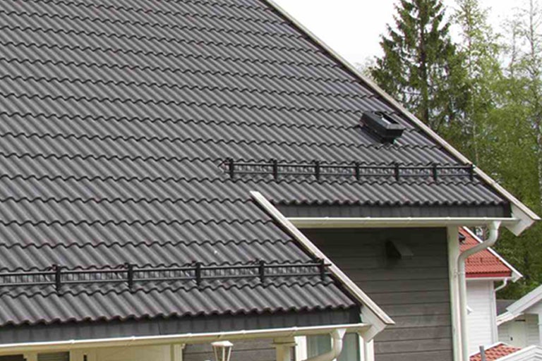 Närbild av ett hus med takpannor och snöskydd.