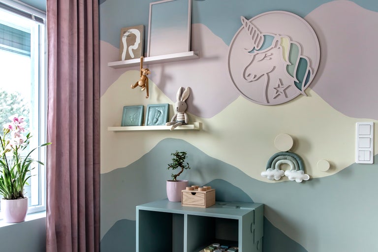 Barnrum med leksaker, möbler och väggdekorationer i mjuka färger