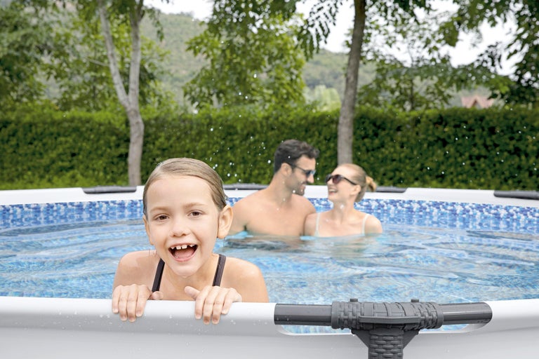 Familjen svalkar sig i en ovanjordisk pool i trädgården.
