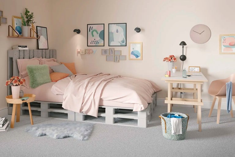 Ljust sovrum med säng av lastpallar, sängbord, skrivbord och dekoration