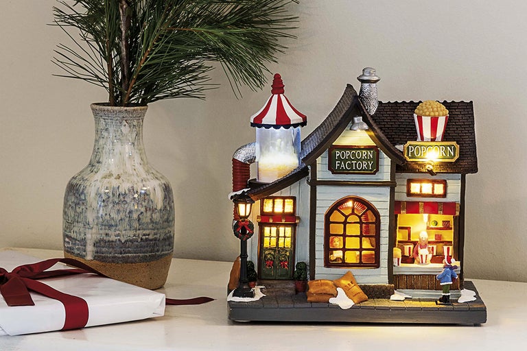 Upplyst julby med popcornfabrik bredvid vas och present