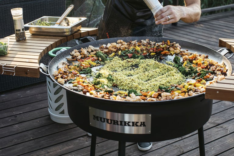 Muurikka grill med tillagad mat och person som tillsätter kryddor