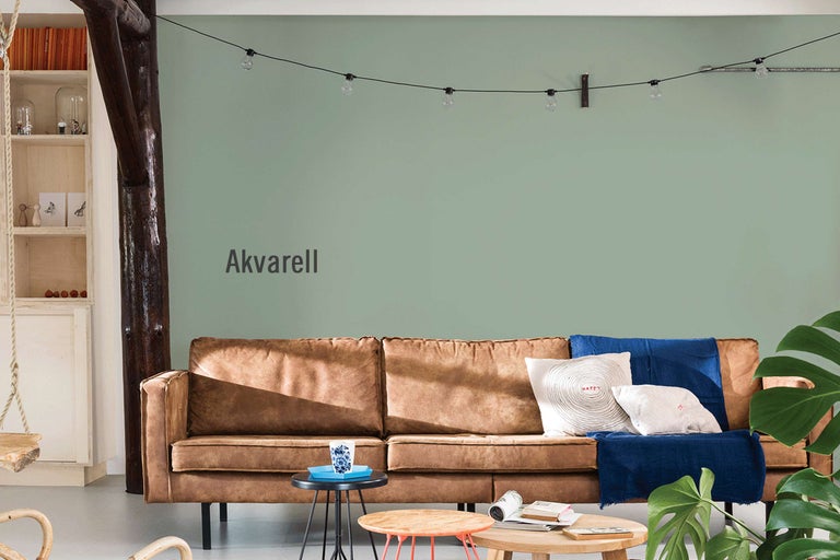 Vardagsrum med brun soffa, dekorativa kuddar och grön väggfärg som heter Aquarell