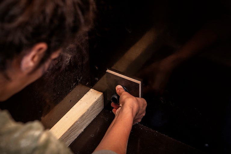 En hand monterar en väggenomföring på en skiva under ett byggprojekt.