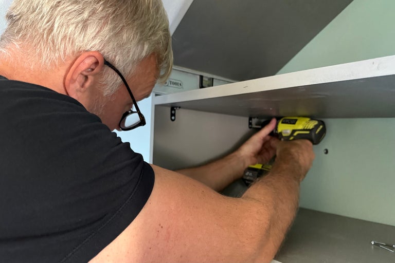 En man fäster en hylla med en sladdlös skruvdragare.