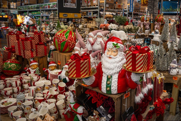 Dekorativ julscen med jultomtefigurer, julgransdekorationer, muggar och presenter i en byggmarknad.