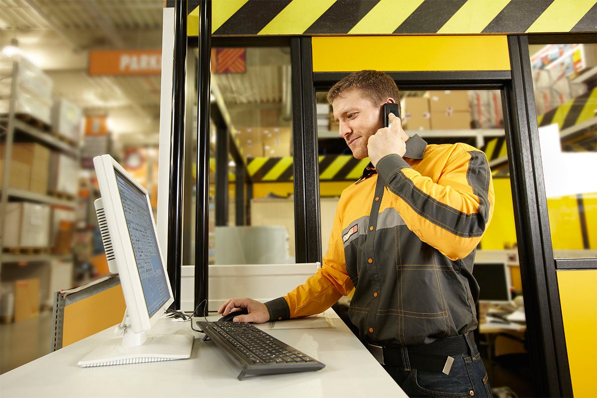 Medarbetare vid informationsdisken med dator och telefon i Hornbach-butiken.