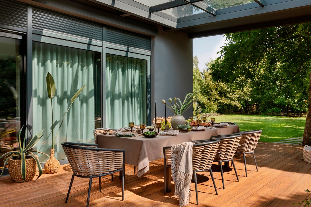 Terrass med matbord, stolar, växter och trädgårdsutsikt