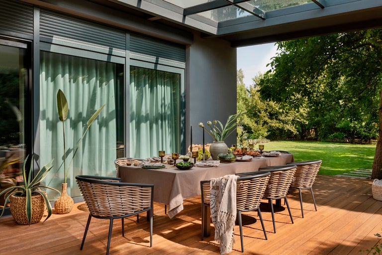 Terrass med matbord, stolar, växter och trädgårdsutsikt