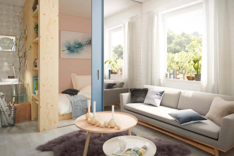 Ljust vardagsrum med soffa, soffbord och rumsavdelare med hylla.