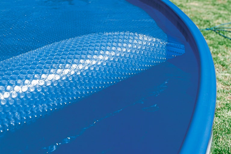 Soltäcke med bubbelstruktur som flyter på poolvattnet.