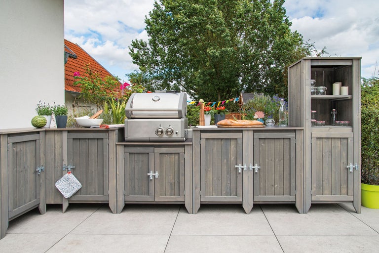 Utomhuskök med grill, skåp och hyllor i trädgården
