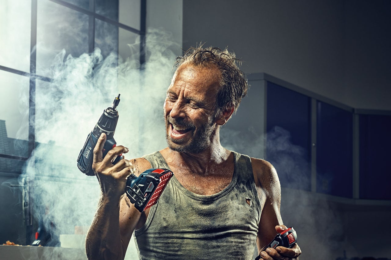 Man håller en sladdlös skruvdragare och en sladdlös sticksåg i handen