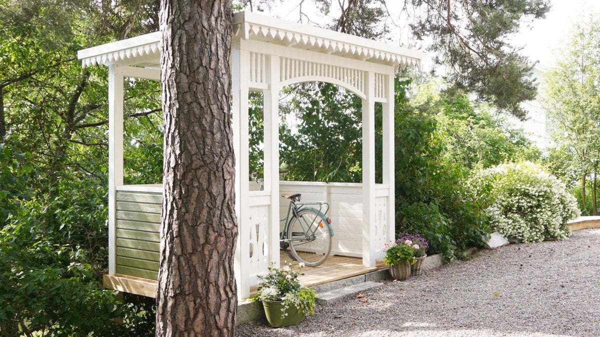 Trädgårdspaviljong i trä med cykel och växter