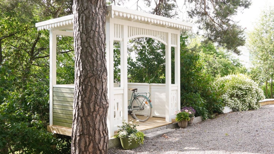 Trädgårdspaviljong i trä med cykel och växter