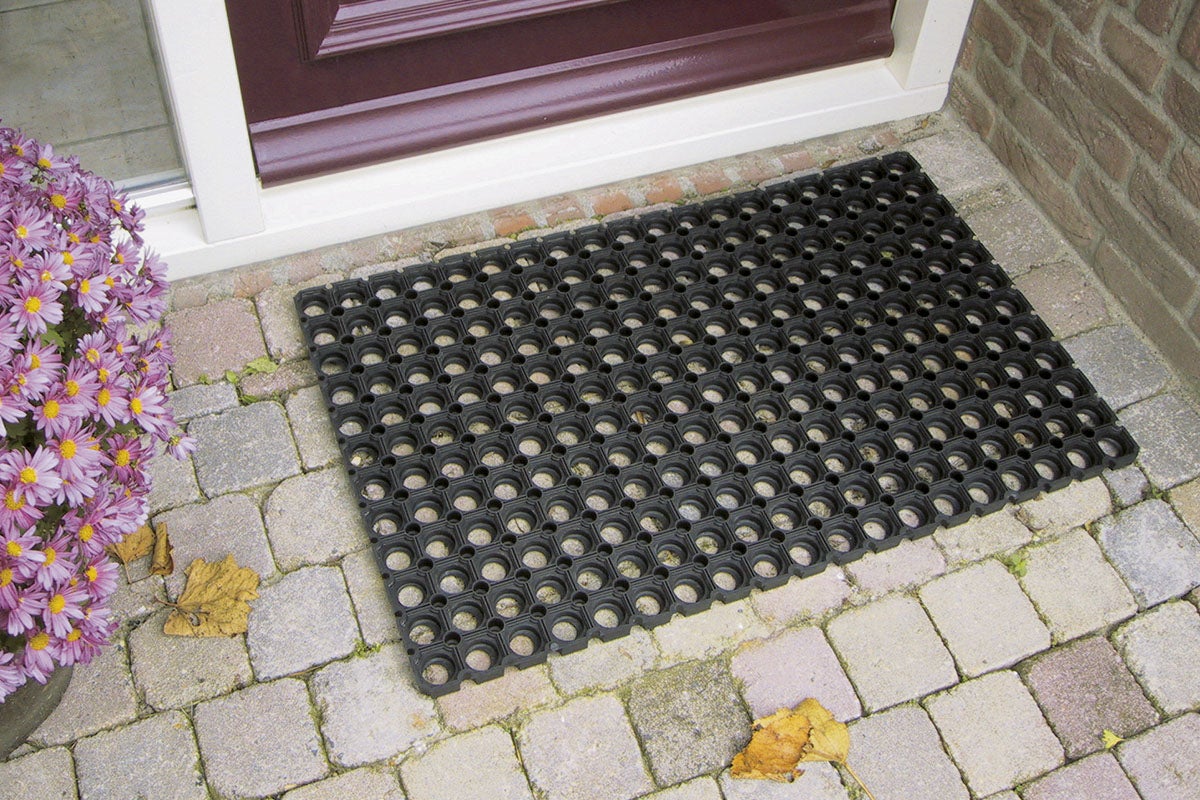 Svart gummimatta med hål framför en ytterdörr