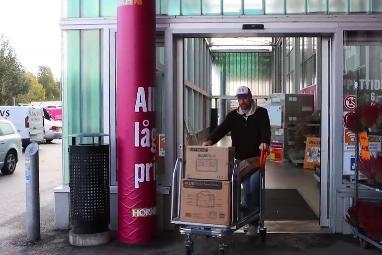 En man skjuter en kundvagn med två BluePalm-generatorer från Hornbachs byggvaruhus.