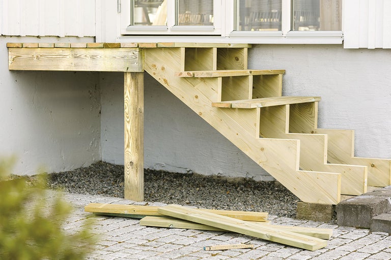 Trädäck med trappa framför ett hus