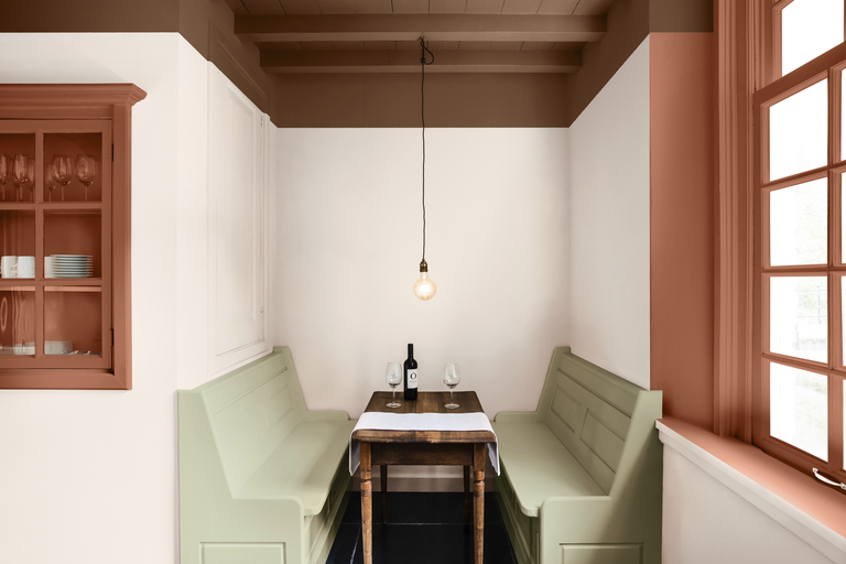 En mysig matplats med träbord, två träbänkar, en vinflaska och glas, framhävd av en dekorativ väggmålning.