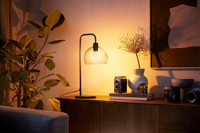 Interiör med bordslampa, växt och dekorativa föremål på en skänk