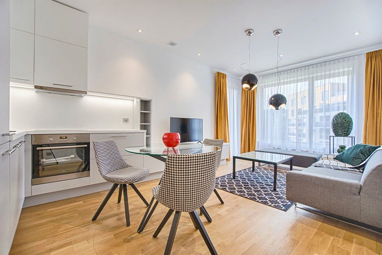 Ljust vardagsrum med pentry, matbord, stolar, soffa och soffbord