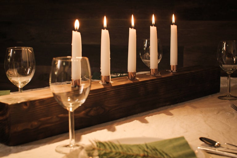 Festligt dukat bord med brinnande ljus i träljusstake och vinglas