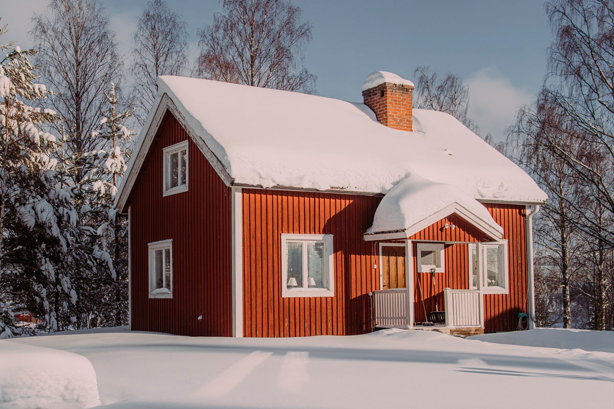 Vinterlandskap med rött trähus och snötäckt tak
