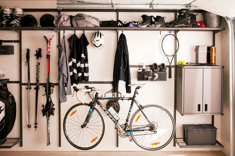 Garage med hyllsystem för förvaring av sportutrustning som skidor, cyklar och tennisracketar.